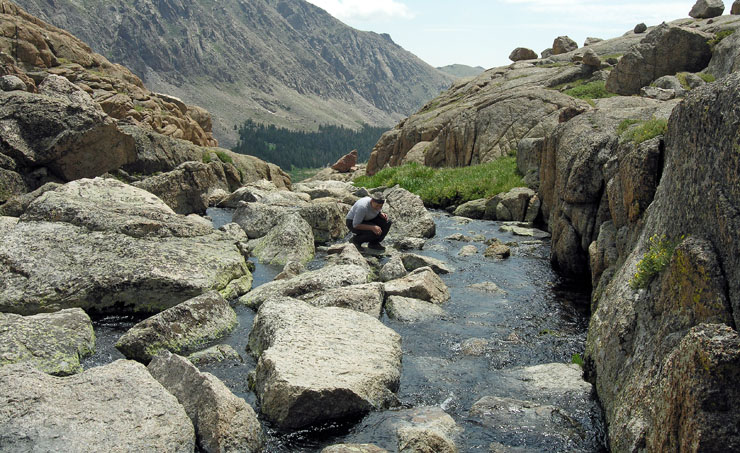 Suzy rock-hopping on creek watching Cutthroat trout at Crystal Lake