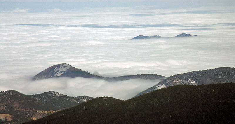 Telephoto shot looking southeast of peak penetrating clouds covering the Colorado Front Range foothills