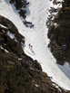 Two people with skis on their packs working up Flattop Gully in Odessa Gorge