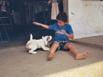 A boy playing with his puppy in front of a souvenir shop at Playas del Coco